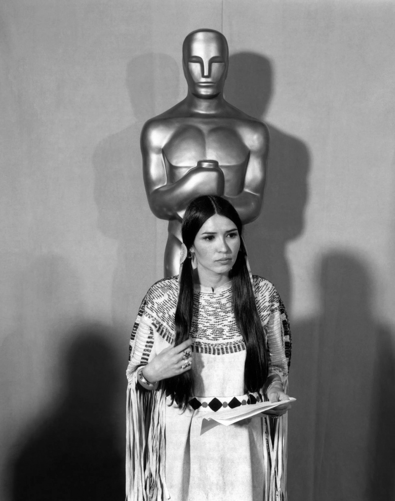 Sacheen Littlefeather drží Marlona Branda's speech refusing to accept his Academy Award for THE GODFATHER in front of a statue of the Academy Award, 1973