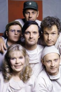   MASH, (también conocido como M*A*S*H*), en el sentido de las agujas del reloj, desde la parte inferior izquierda: Loretta Swit, Larry Linville, Wayne Rogers, Alan Alda, McLean Stevenson, Gary Burghoff