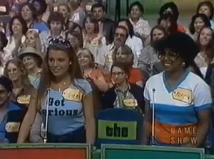 Vanna White על The Price is Right, נראתה כשהיא לובשת חולצה עם הכתובת Get Serious