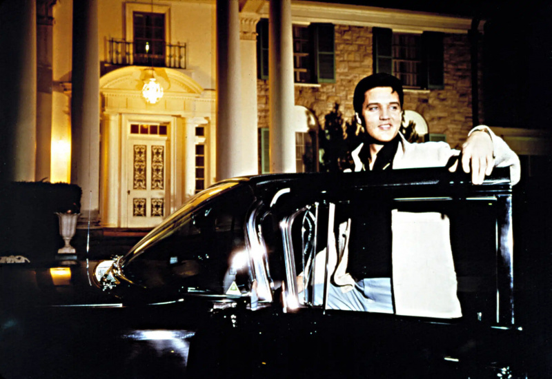  ELVIS PRESLEY, nastupujúci do svojho auta Cadillac pred Gracelandom, približne začiatkom 60. rokov
